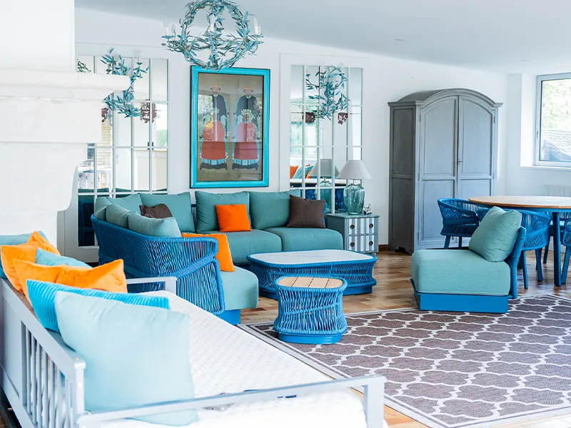 Canapé turquoise avec coussins bordeaux dans le Pool House, ambiance cosy et chic